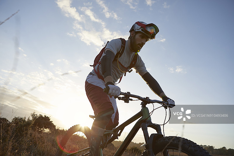 在荒地上骑山地自行车的男人图片素材