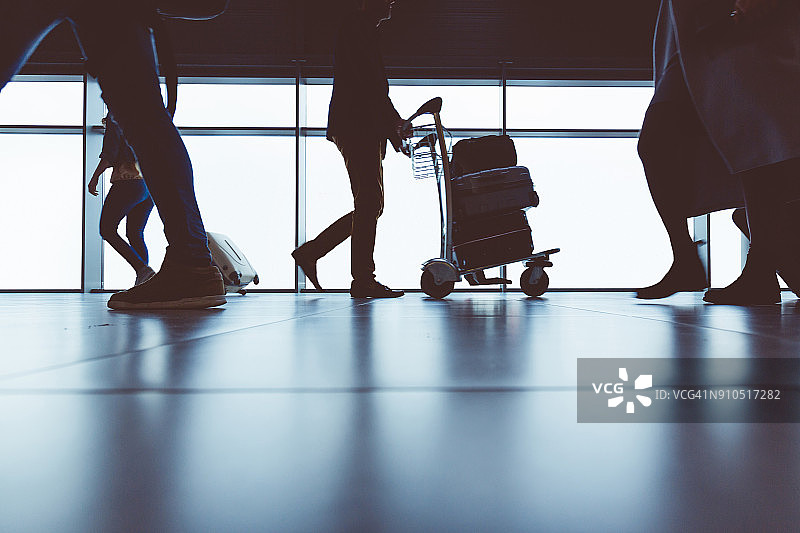 在机场航站楼拖着行李箱行走的人们侧视图图片素材