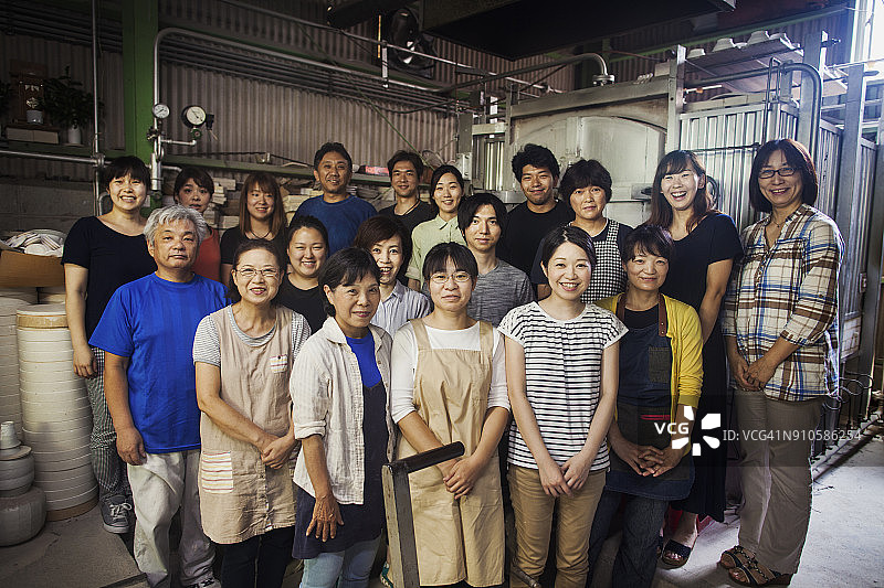 日本瓷器工坊员工在窑炉前合影，对着镜头微笑图片素材
