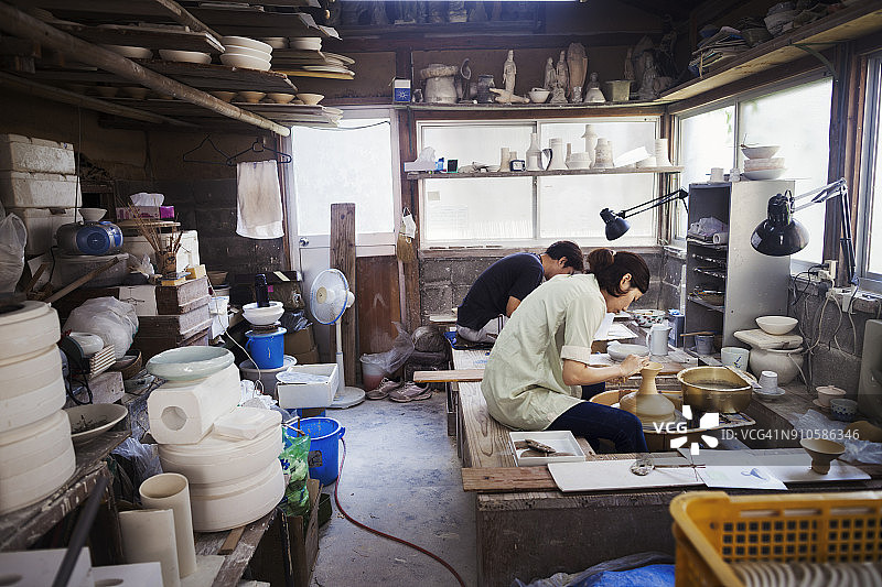 女人在日式瓷器工作室工作，坐在陶轮旁，拉坯图片素材