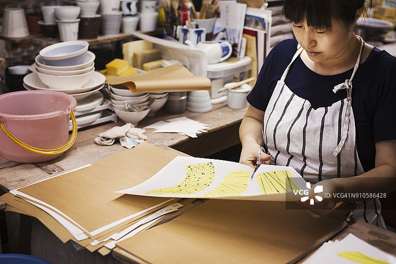 女人坐在日本瓷器作坊里，用剪刀剪出设计图案图片素材