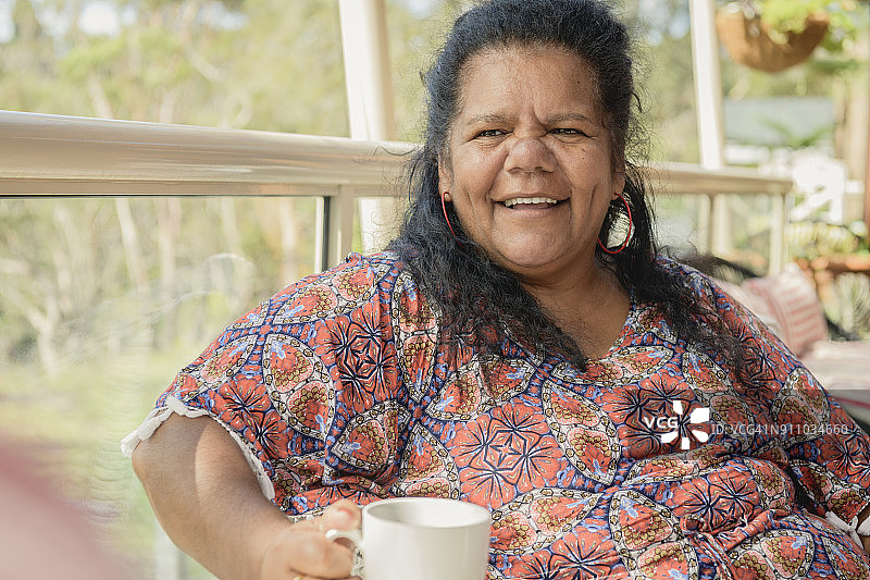 中年原住民妇女拿着咖啡杯望向远方图片素材