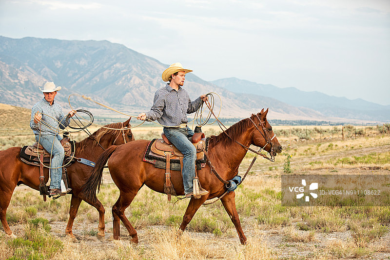 两名牛仔在犹他州牧场热身练习套索图片素材