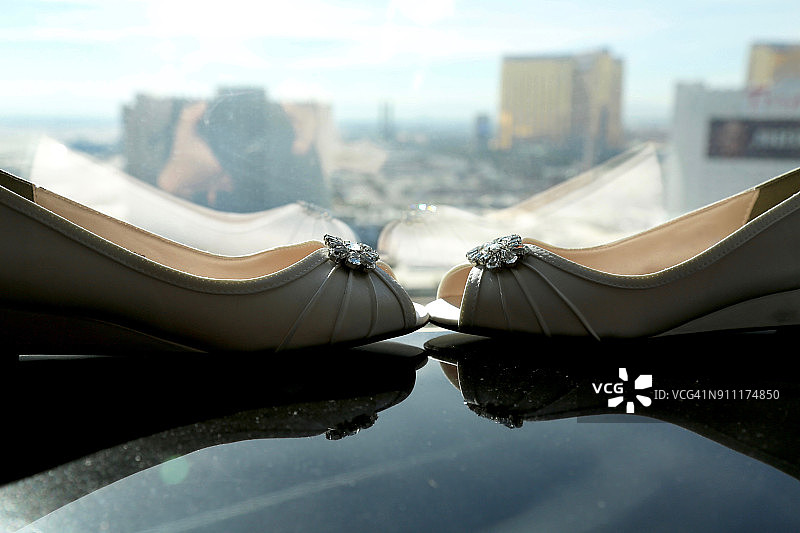 坡跟鞋：新娘的精致礼鞋，窗边静物，背景是拉斯维加斯城市风光图片素材