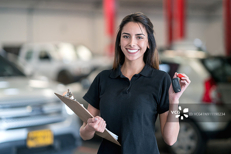女修理工在车库工作并拿着车钥匙图片素材