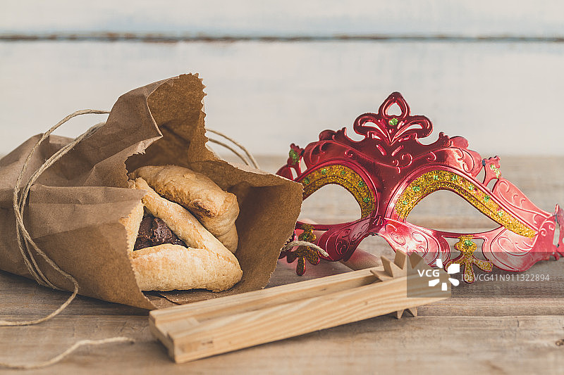 犹太教普珥节组成，哈曼塔 شن、面具和响板在复古木纹背景上，有复制空间图片素材