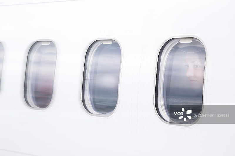 创意双重曝光：旅行者女子在飞机上透过窗户观看目的地机场着陆时的窗外景色图片素材