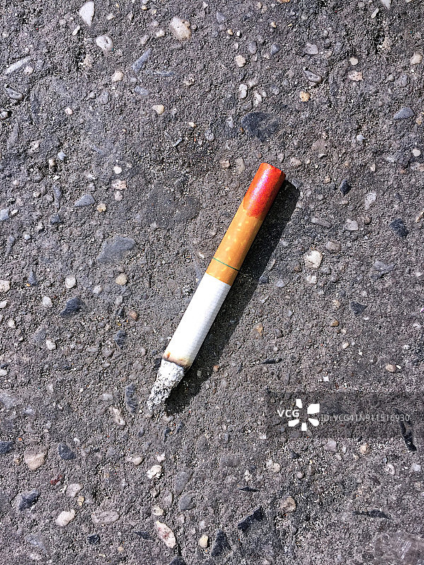 地面上带有口红印的点燃的香烟图片素材