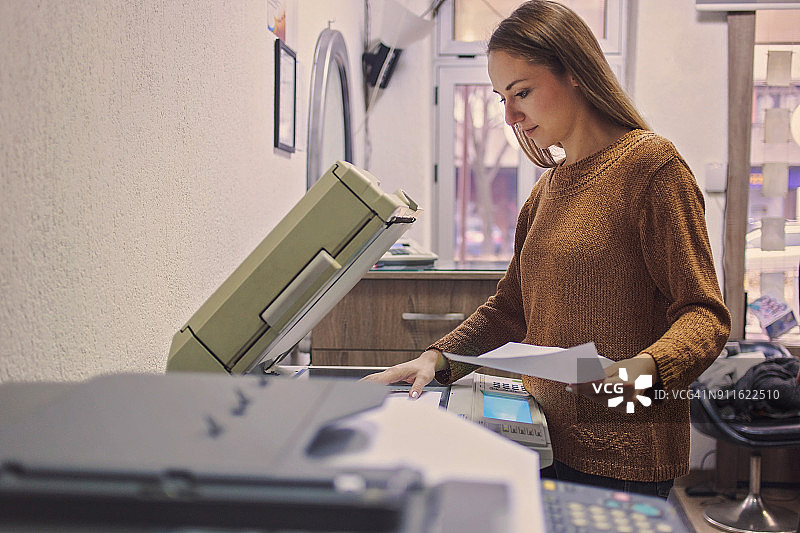 女人将纸放入复印机图片素材