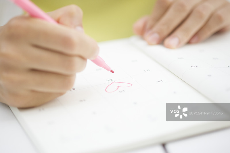 女人在日程本上画心形图案图片素材