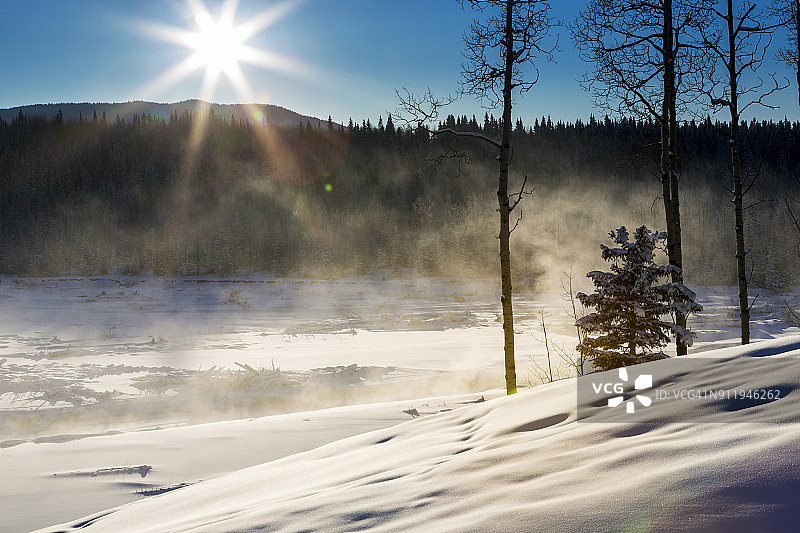 白雪覆盖的河边山坡，雾气升腾，阳光普照，蓝天白云，布拉格克里西侧图片素材