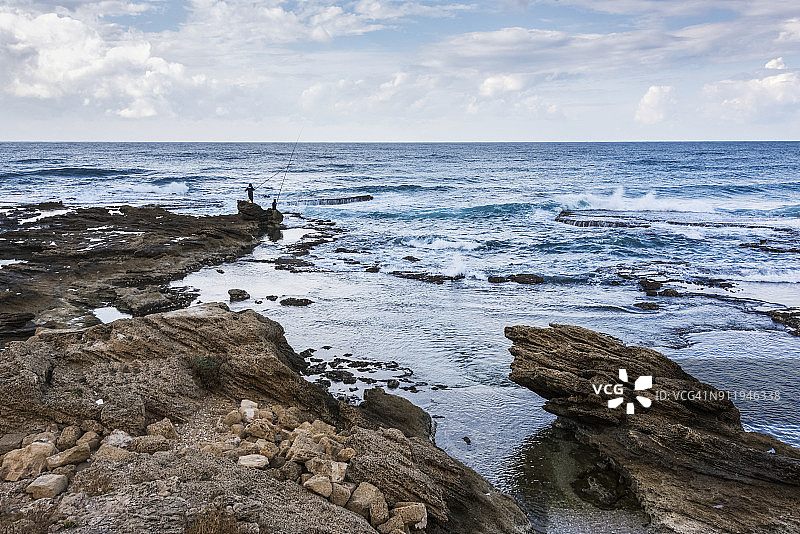 男士在水边岩石上钓鱼图片素材