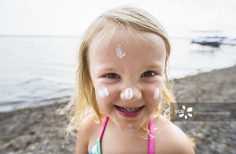 一位涂着防晒霜的年轻白人女孩在塞内卡湖边拍照图片素材