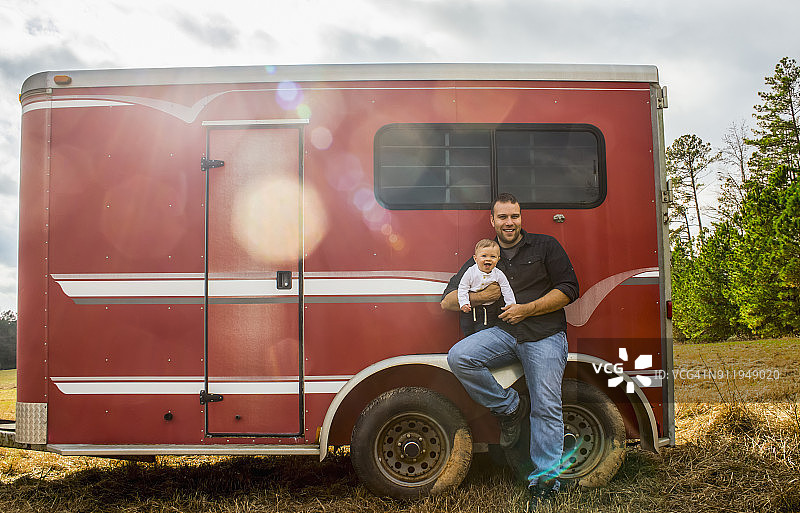一个白人男婴和他的父亲坐在红色马拖车的轮舱上图片素材