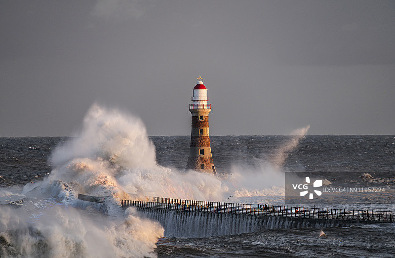波浪拍打着码头尽头的罗克灯塔图片素材
