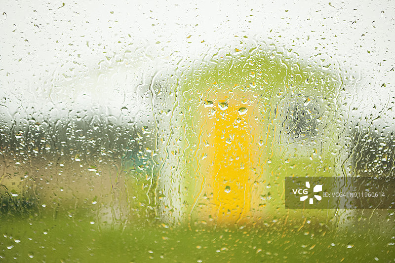 雨滴打湿的窗户后的小绿房子和黄色门窗图片素材
