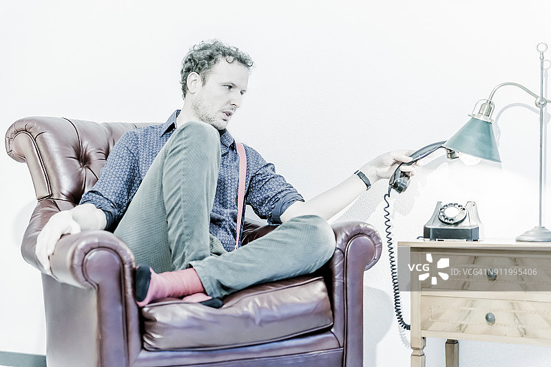 坐在扶手椅上挂断电话的男人图片素材