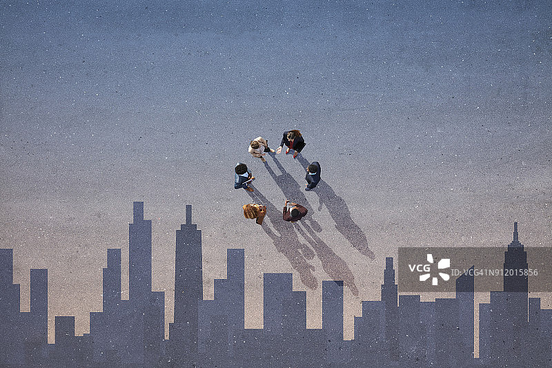 商务人士在沥青地面上围成一圈，背景是天际线图片素材