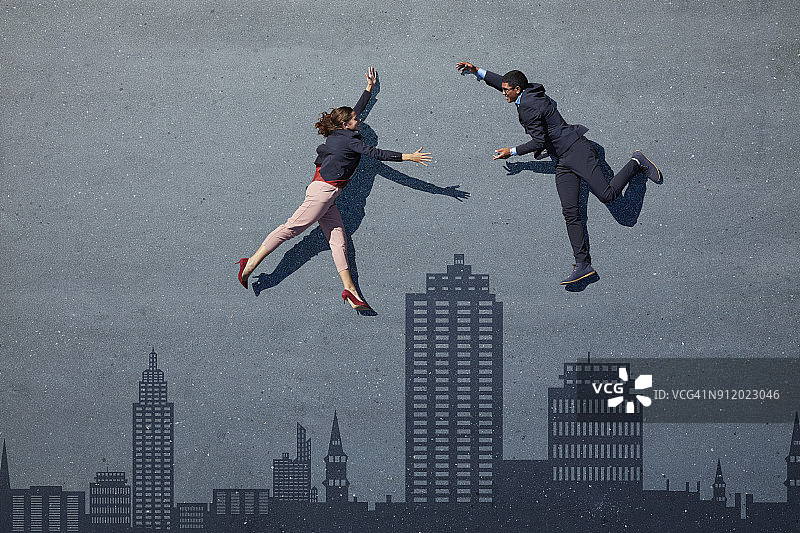 商人们躺在绘有天际线图案的沥青地面上，试图拥抱彼此图片素材