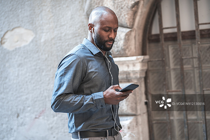 听着音乐，手里拿着手机的商人图片素材