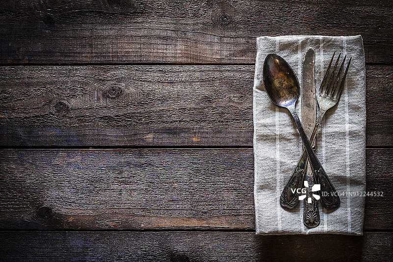 乡村木桌上纺织餐巾上的复古银器俯视图图片素材