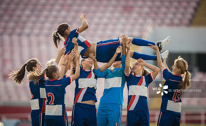 快乐的女子足球队在赛场上庆祝胜利图片素材