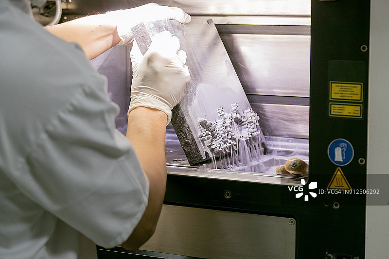牙科技师从3D粉末打印机中取出假牙图片素材