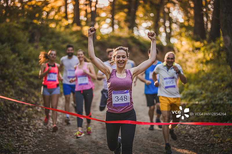 快乐的女跑步者赢得马拉松比赛并冲过终点线图片素材