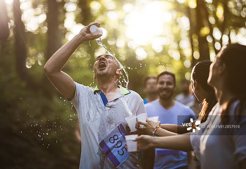 马拉松男选手往脸上浇水，给自己补充水分图片素材