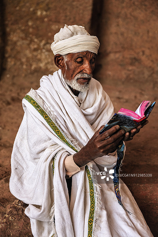 拉利贝拉岩石教堂的牧师阅读圣书图片素材