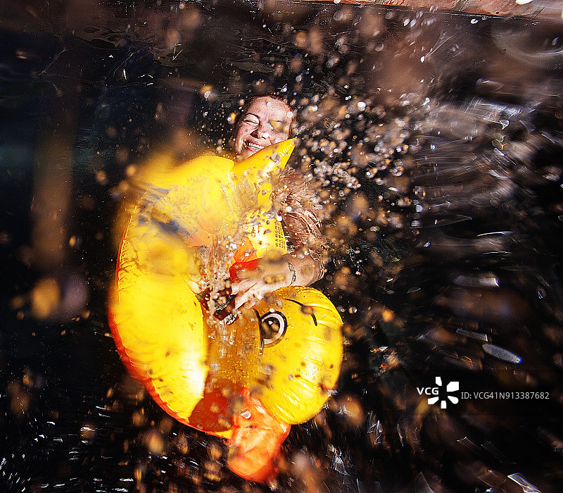 在游泳池里和塑料鸭子一起躺着的女人图片素材