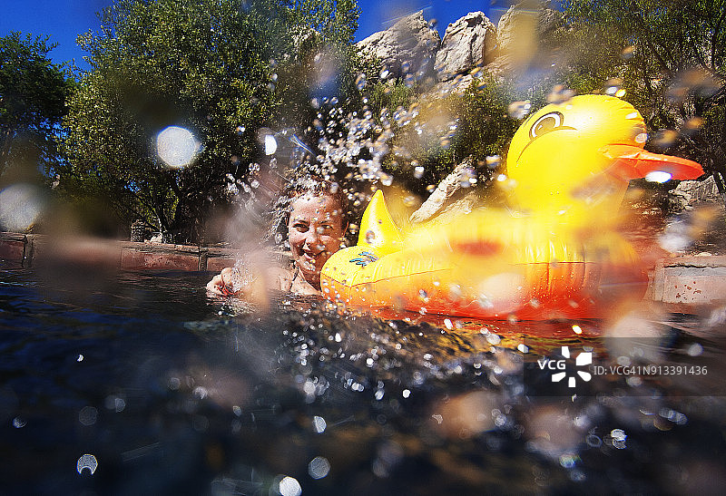 在游泳池里被黄色橡皮鸭溅到的女人图片素材