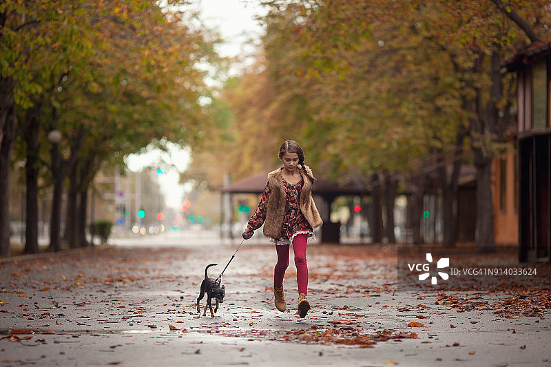 雨天在公园里和幼犬一起奔跑的女孩图片素材