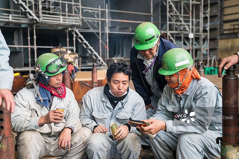 钢铁工人焊接休息时一起看智能手机图片素材