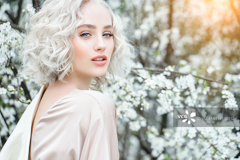 春天灌木丛背景上的美丽女孩图片素材