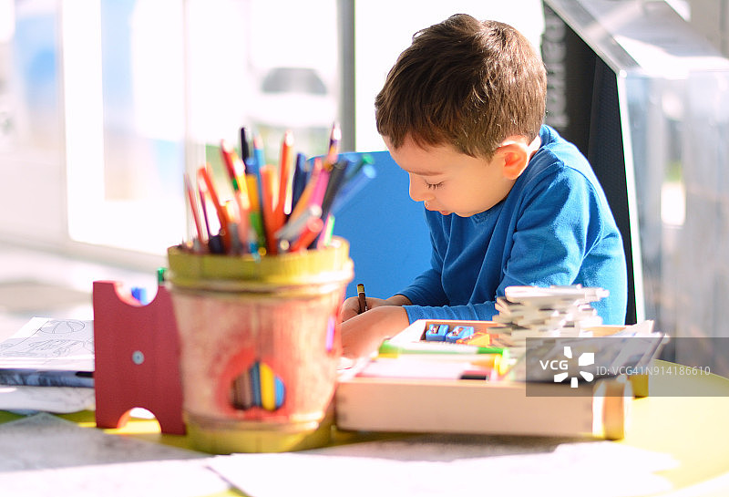 在游戏室里在纸上涂色的儿童图片素材