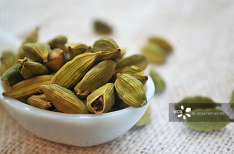陶瓷勺中的豆蔻香料特写图片素材