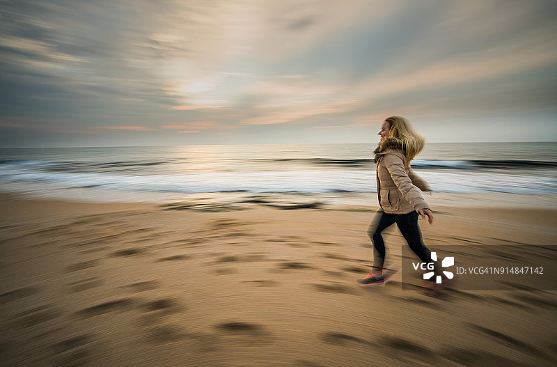 一位女子在海滩上奔跑，呈现出模糊的动感图片素材