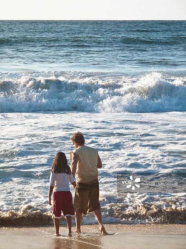 男人和女孩在看冲浪。图片素材