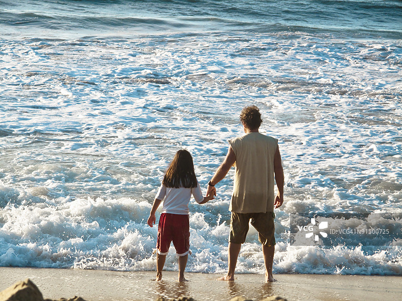 男人和女孩在看冲浪。图片素材