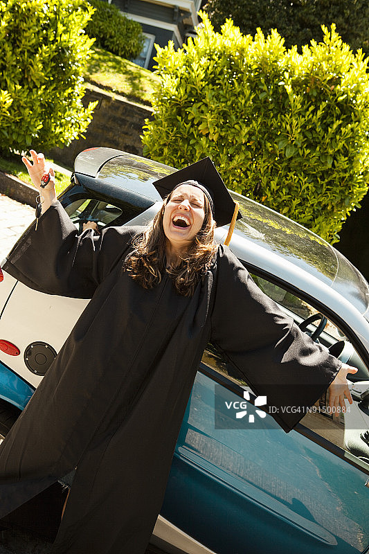 戴着帽子和学士服，开着智能汽车的女人图片素材