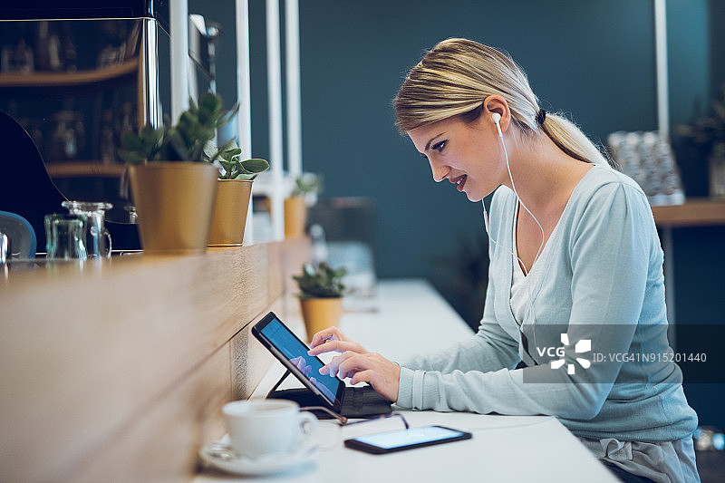 年轻女人在咖啡厅使用平板电脑图片素材