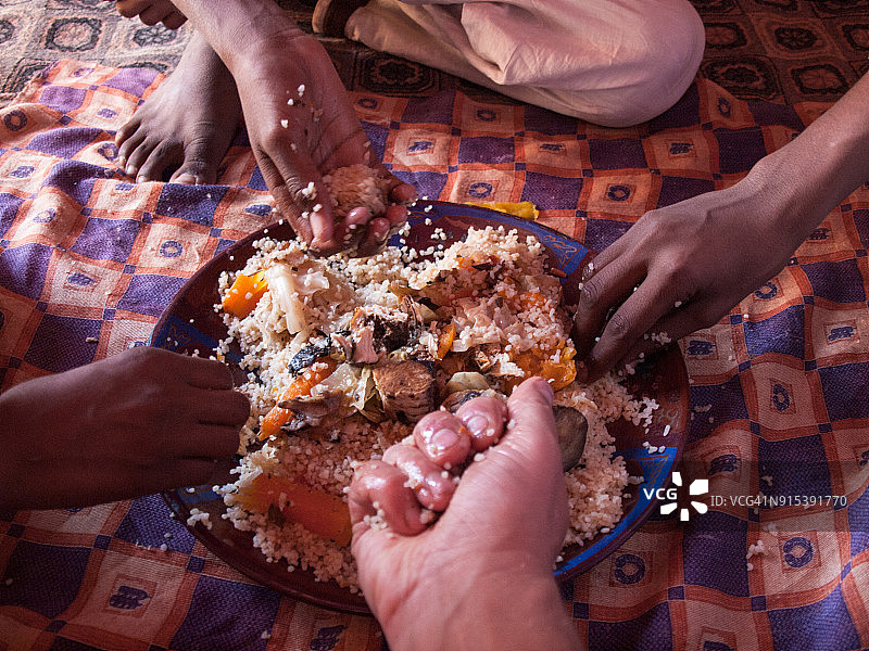 三位当地人和一位游客一起用手分享一份塞内加尔烩饭图片素材
