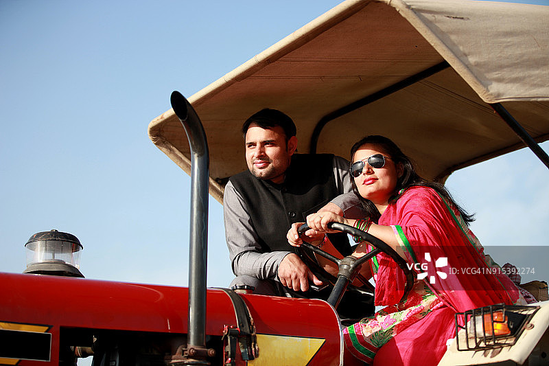 印度男女农民坐在田野里的拖拉机上图片素材