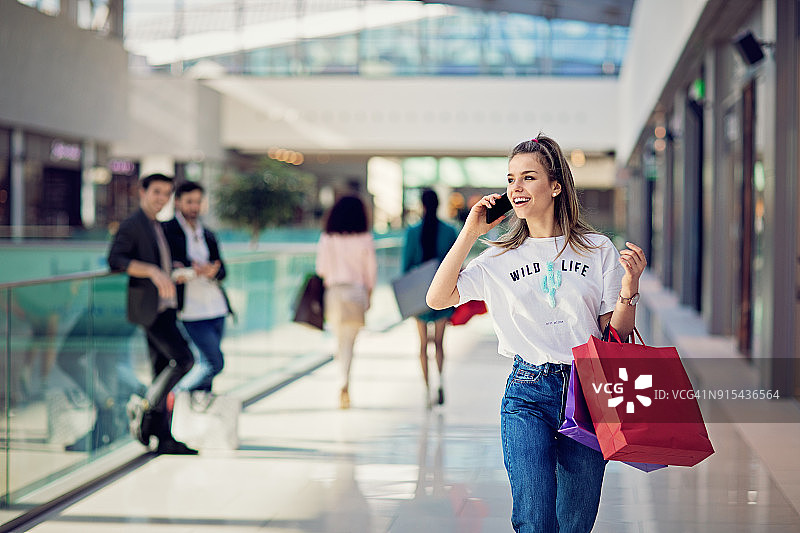 在购物中心使用手机的购物女孩图片素材