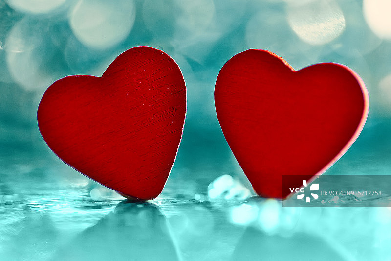 水蓝色散景背景上的两个红色心形，情人节主题图片素材