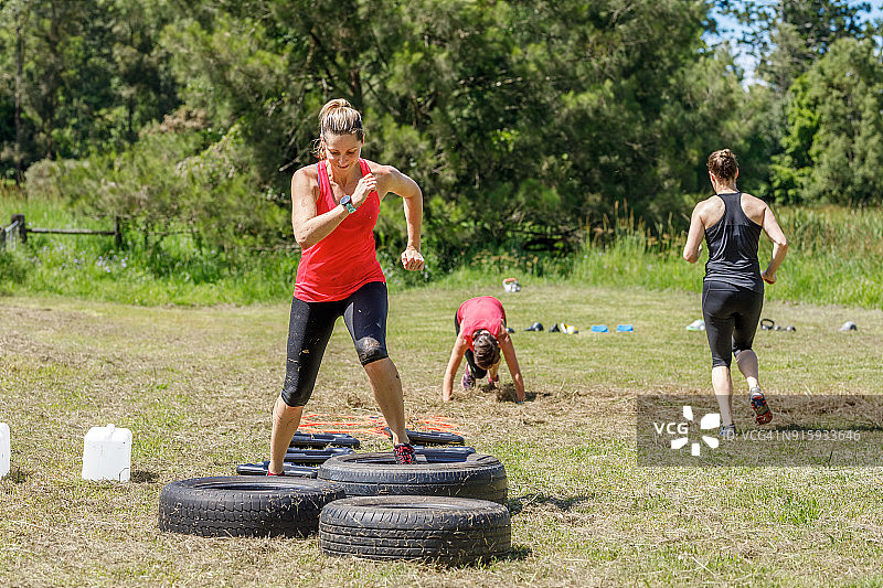 妇女完成户外训练课程障碍赛图片素材