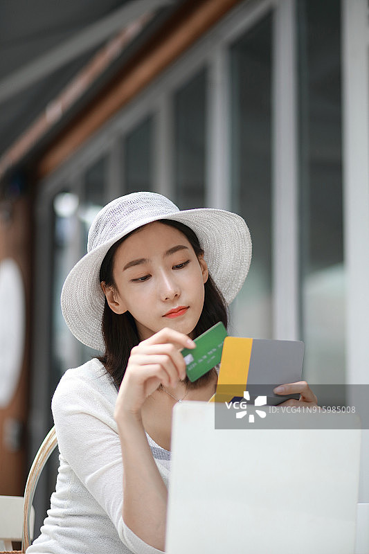 女人在咖啡馆拿着信用卡和银行存折图片素材