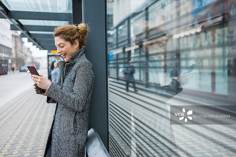 女人在公交车站使用手机喝咖啡图片素材
