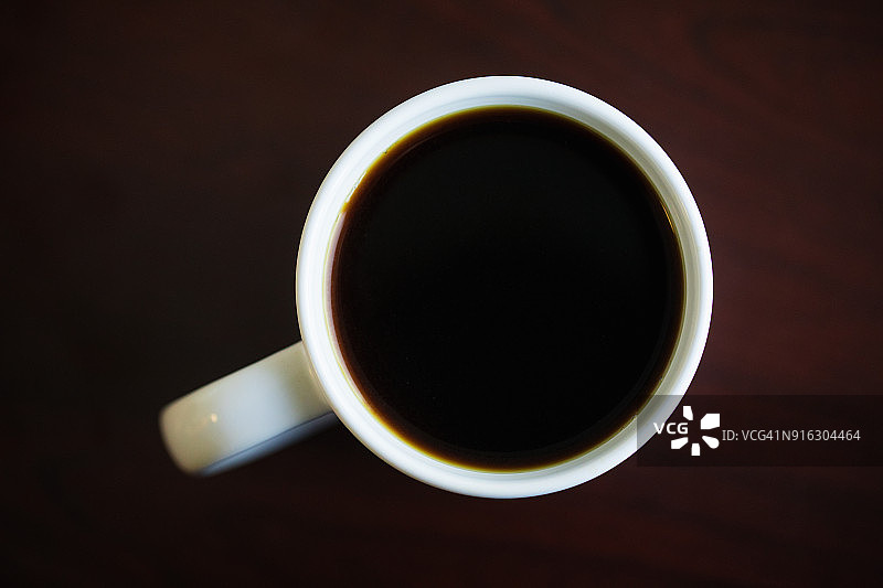 办公桌上白色马克杯中的黑咖啡俯视图图片素材